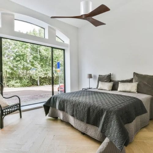 Destratificateur atlas fan blanc et bois dans une chambre classique avec grande baie vitrée